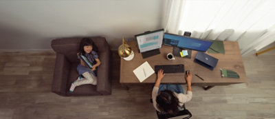 Una persona está trabajando en un escritorio con dos monitores de ordenador, un teclado, una taza de café y unos cuantos materiales de oficina.