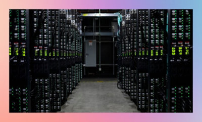 Een gang tussen rijen serverracks in een datacenter met brandende lampjes op apparatuur.