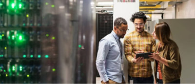 Eine Gruppe Männer, die auf ein Gerät schaut, während einer von ihnen ein Tablet in der Hand hält.