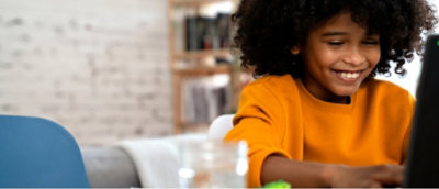 Une personne en chemise jaune assise à une table, à l’intérieur, avec un arrière-plan aux contours flous.