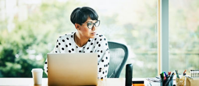 A person with short black hair and glasses wearing a white shirt with black polka dots 