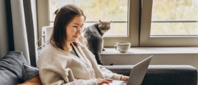 Une fille assise devant un ordinateur avec un chat en arrière-plan