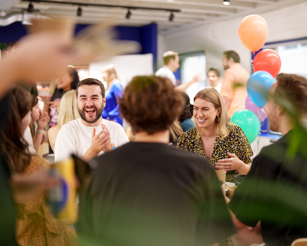 A group of Figmates cheering with balloons in an office