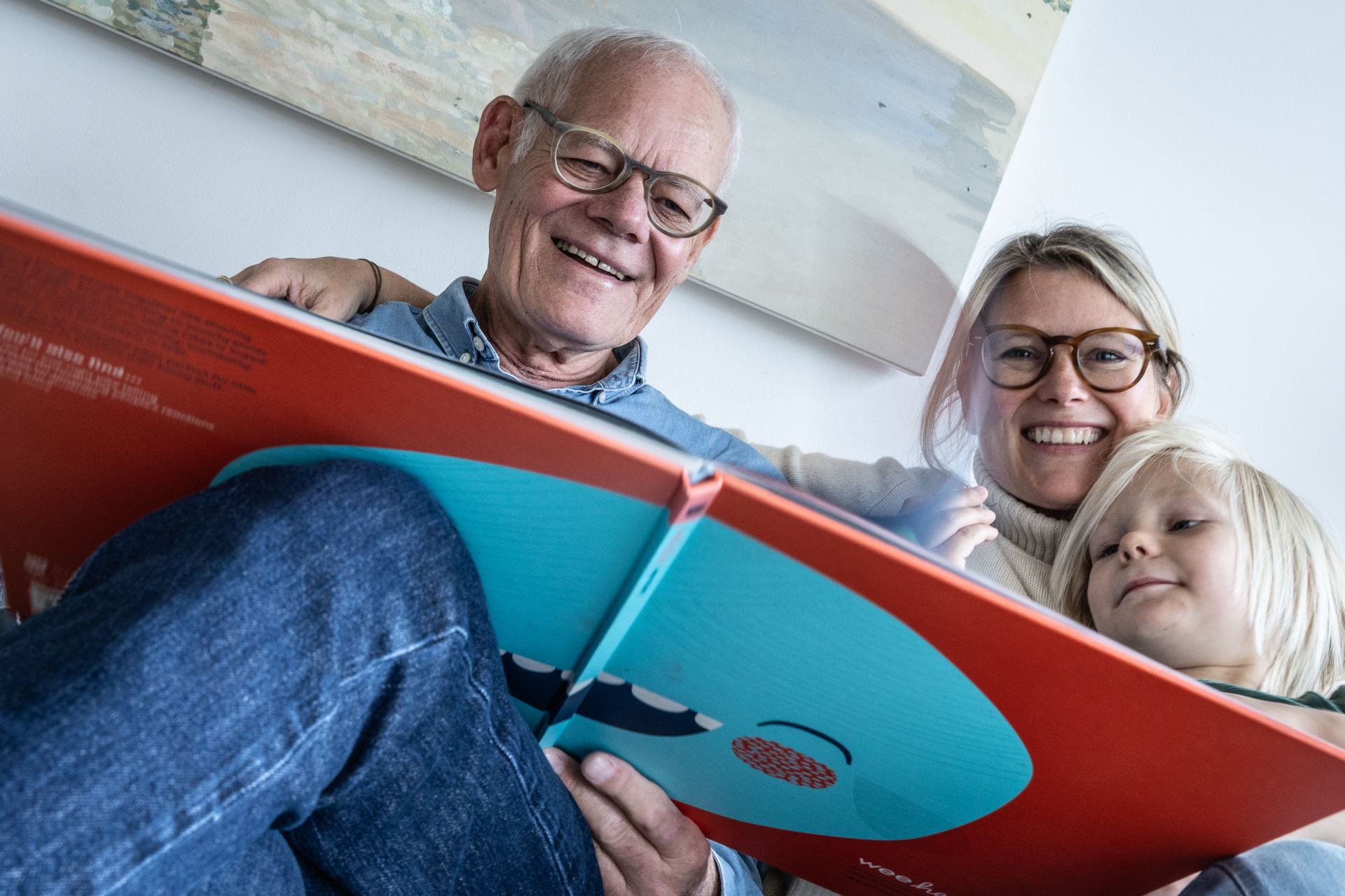 Shaping health across generations 001 WEB00920 Three generations reading a book on the couch