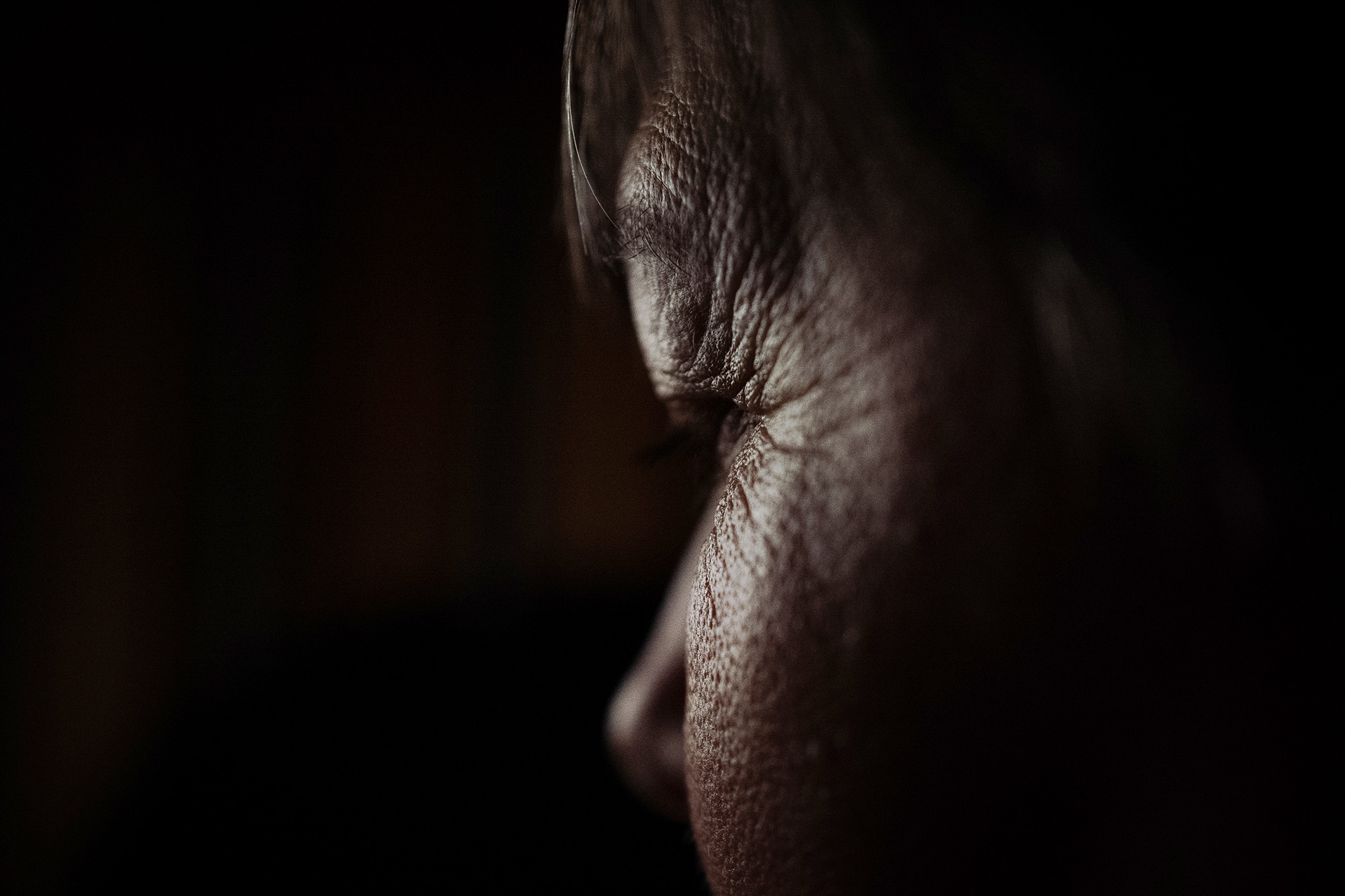 Profile of a woman's face, sihouetted and in shadow.