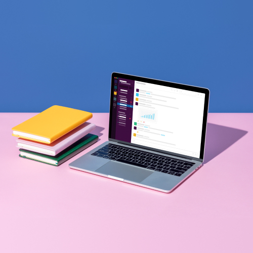 Slack 애플리케이션이 실행 중인 열린 노트북 옆의 책 더미