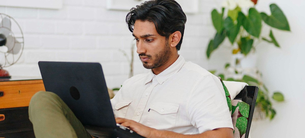 Featured image: A person wearing a white shirt looking at a laptop screen and typing.