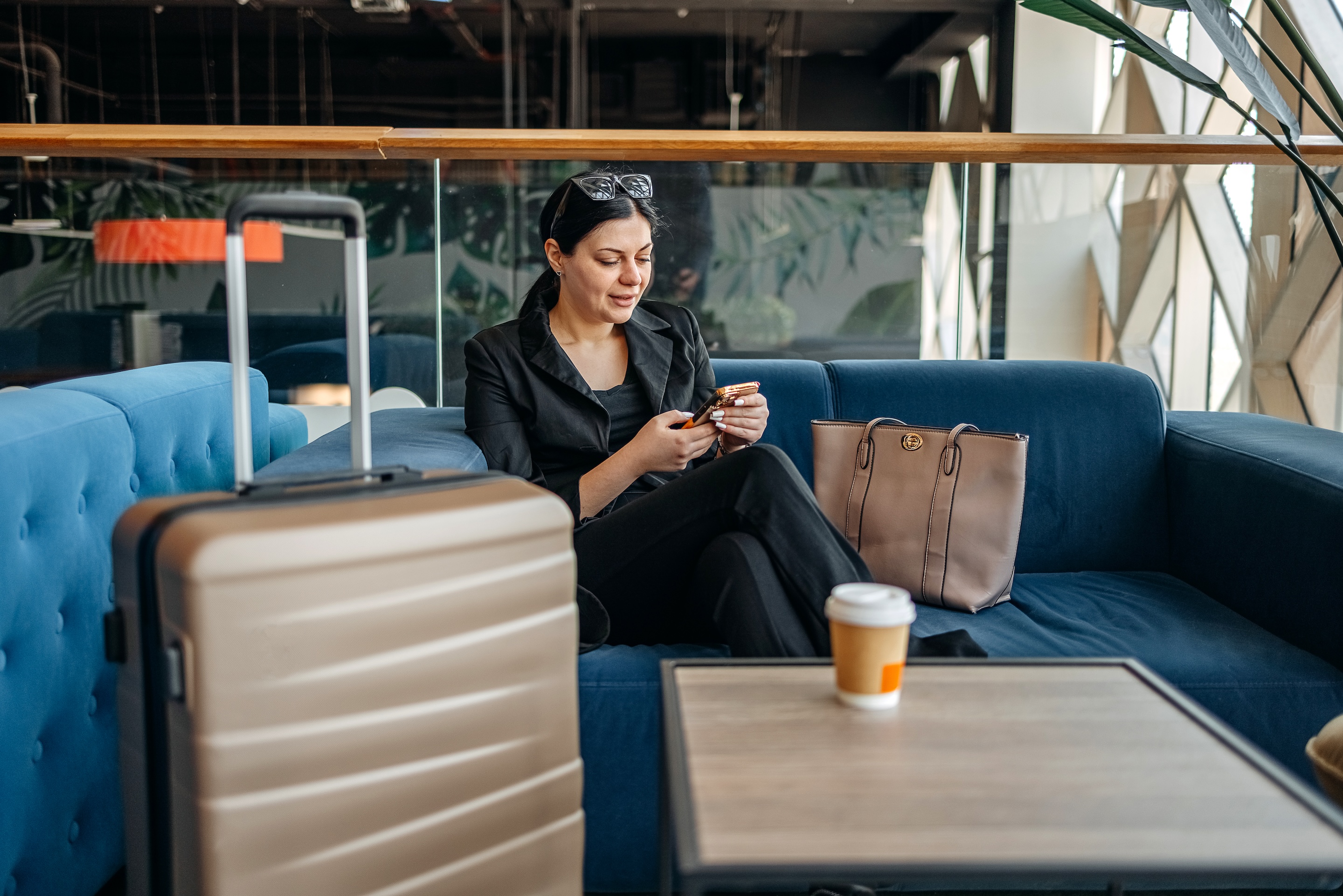 Young woman with suitcase close to her in an airport lounge