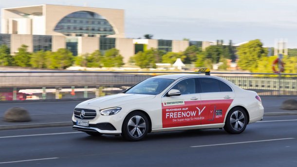Ein Taxi mit Freenow-Werbung in Berlin, im Hintergrund das Bundeskanzleramt.