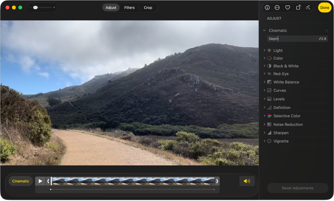 A video in editing view with a frame viewer below. The Cinematic button and Play button are to the left of the frame viewer and the Audio button is on the right. Adjustment tools appear in the Adjust pane.