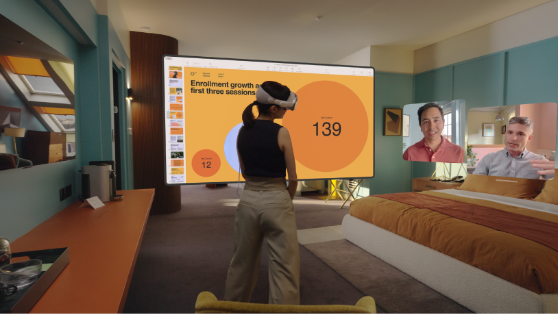 Una persona che indossa Apple Vision Pro durante una chiamata FaceTime. I riquadri degli altri partecipanti alla chiamata sono visibili accanto a uno schermo condiviso.