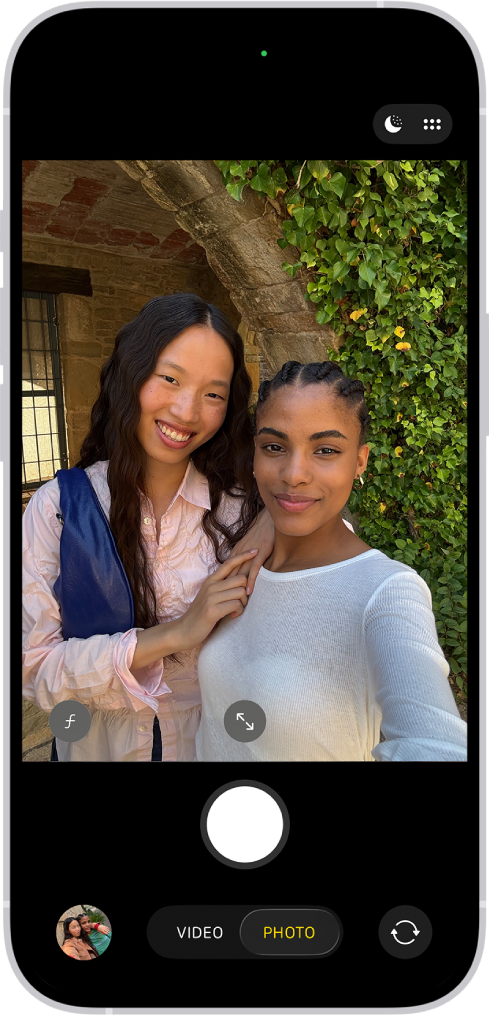 Obrazovka aplikace Fotoaparát v režimu Foto. Fotoaparát zabírá lidi, kteří si právě pořizují selfie.