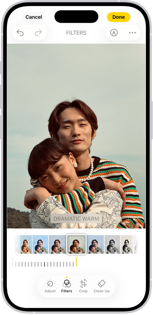 ਕੇਂਦਰ ਵਿੱਚ ਤਸਵੀਰ ਵਾਲੀ “ਸੋਧ ਕਰੋ” ਸਕਰੀਨ। ਸਕਰੀਨ ਦੇ ਹੇਠਲੇ ਪਾਸੇ, ਖੱਬੇ ਤੋਂ ਸੱਜੇ, “ਅਡਜਸਟ ਕਰੋ”, “ਫ਼ਿਲਟਰ ਕਰੋ”, “ਕ੍ਰੌਪ ਕਰੋ” ਅਤੇ ”ਸਾਫ਼ ਕਰੋ” ਬਟਨ ਹਨ। “ਫ਼ਿਲਟਰ ਕਰੋ” ਬਟਨ ਚੁਣਿਆ ਗਿਆ ਹੈ। ਤਸਵੀਰ ਦੇ ਹੇਠਾਂ ਵੱਖ-ਵੱਖ ਫ਼ਿਲਟਰ ਵਿਕਲਪ ਹਨ। ਡ੍ਰੈਮੈਟਿਕ ਵਾਰਮ ਚੁਣਿਆ ਗਿਆ ਹੈ ਅਤੇ ਫ਼ਿਲਟਰ ਦੀ ਤੀਬਰਤਾ ਨੂੰ ਅਡਜਸਟ ਕਰਨ ਲਈ ਇੱਕ ਸਲਾਈਡਰ ਹੈ। “ਰੱਦ ਕਰੋ” ਬਟਨ ਸਕਰੀਨ ਦੇ ਉਪਰਲੇ-ਖੱਬੇ ਕੋਨੇ ਵਿੱਚ ਹੈ ਅਤੇ “ਹੋ ਗਿਆ” ਬਟਨ ਉਪਰਲੇ-ਸੱਜੇ ਕੋਨੇ ਵਿੱਚ ਹੈ।