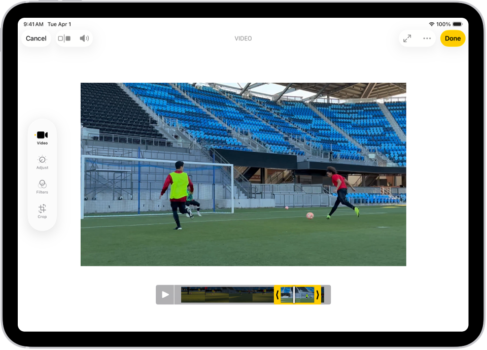 A Fotók app Szerkesztés képernyője, középen egy lejátszott videóval. A videó képkocka-nézegetője a videó aljánál található, és egy sárga körvonal jelenik meg a kijelölt képkockák körül, amellyel a képkockák belefoglalhatók a megvágott videóba. A képernyő bal oldalán a következő gombok láthatók: Videó, Beállítás, Szűrők és Körbevágás; a Videó gomb van kijelölve.