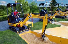 a man sitting on the back of a yellow bulldozer next to other equipment