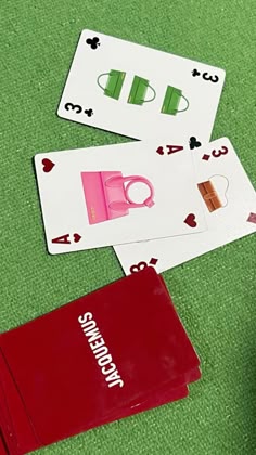 some cards and scissors are laying on the green carpet next to two red folders