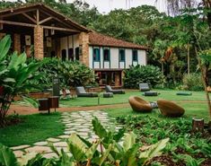 an outdoor area with chairs and trees in front of a house that is surrounded by greenery