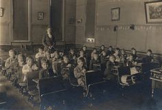an old black and white photo of a classroom full of children sitting at desks