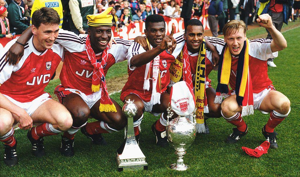 Martin Hayes, Kevin Campbell, Paul Davis, David Rocastle and Lee Dixon celebrate winning the 1990-91 league championship with Arsenal by sitting behind the trophies