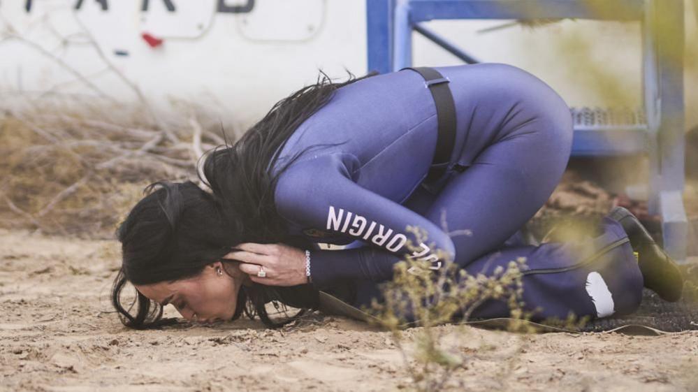 Katy Perry kisses the ground after in front of the Blue Origin rocket after landing back from space.