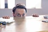 Scared looking office consultant hides under desk