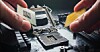 Hands swapping out a CPU on a motherboard