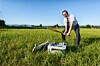 A man destroys a printer with a baseball bat in an open field.