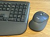 A Logitech keyboard and a matching ergonomic mouse sit side by side on a wood tabletop.