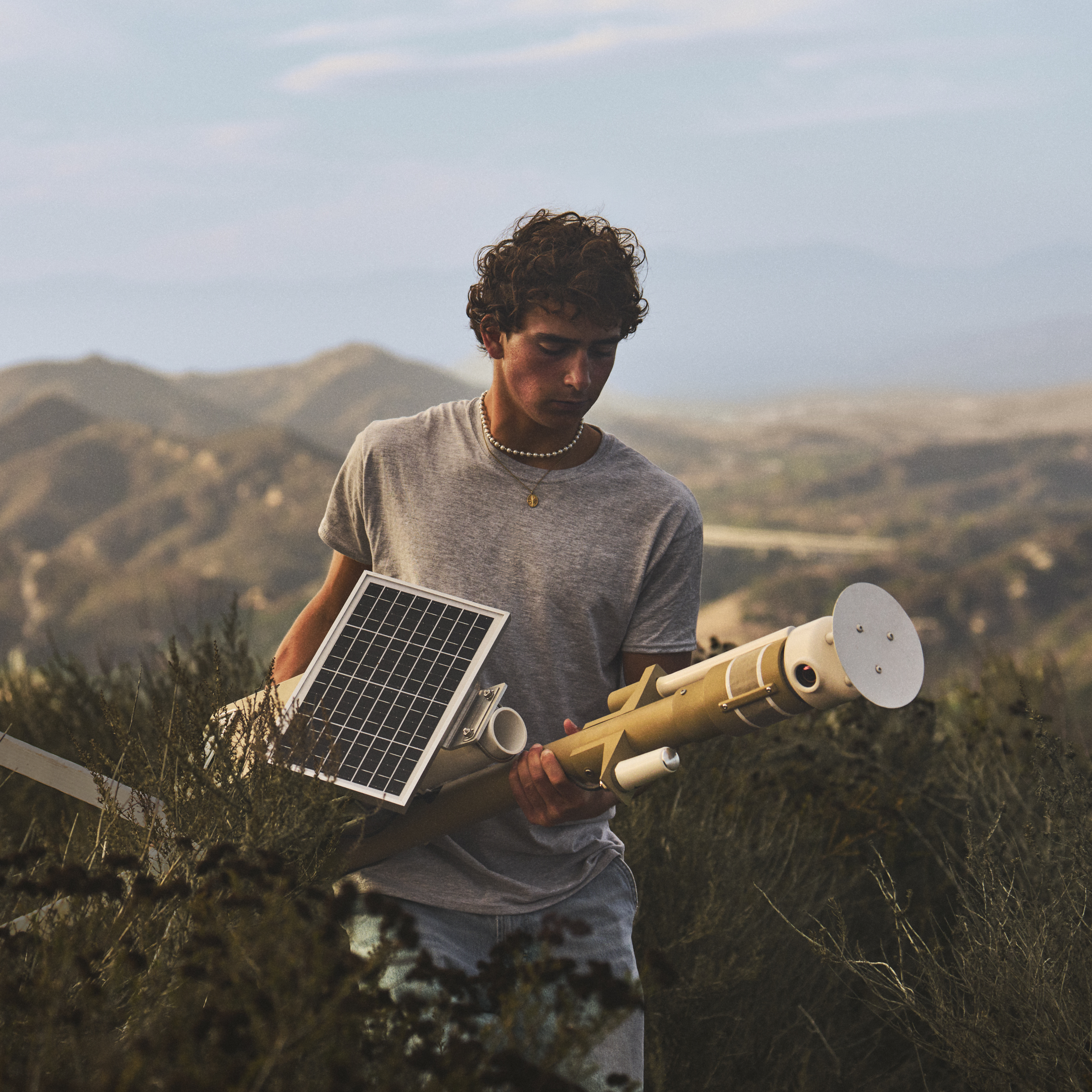Ryan Honary transportă un senzor cu energie solară pentru detectarea incendiilor de vegetație prin dealurile aride.