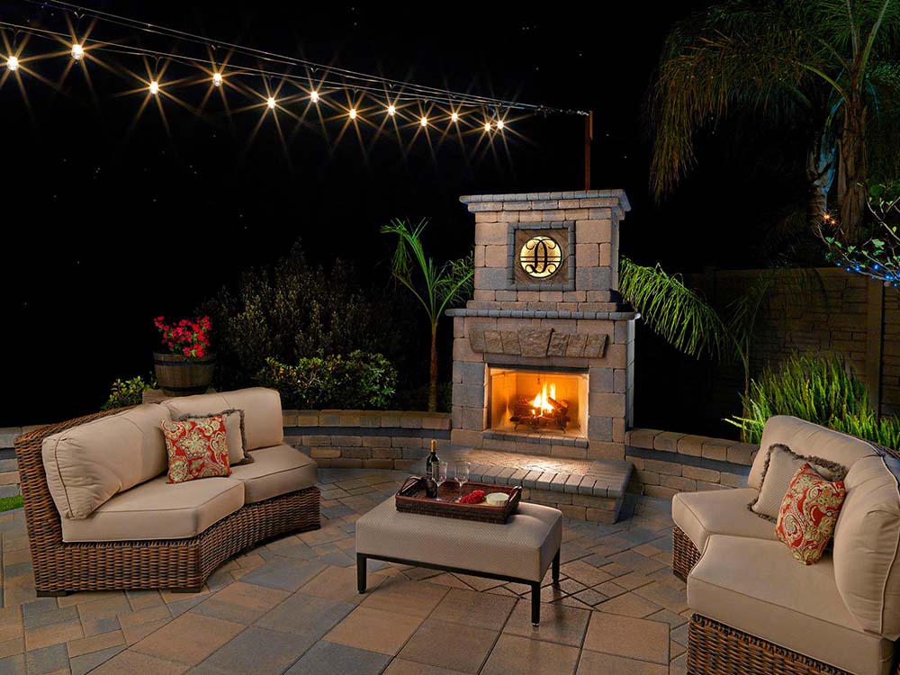 Cozy outdoor fireplace on paver patio with outdoor lighting