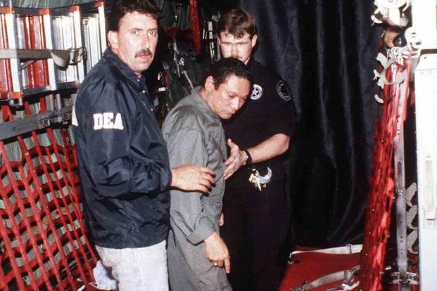 Noriega being escorted onto a U.S. Air Force aircraft by agents from the U.S. Drug Enforcement Administration (DEA) on January 3, 1990. (Department of Defense)