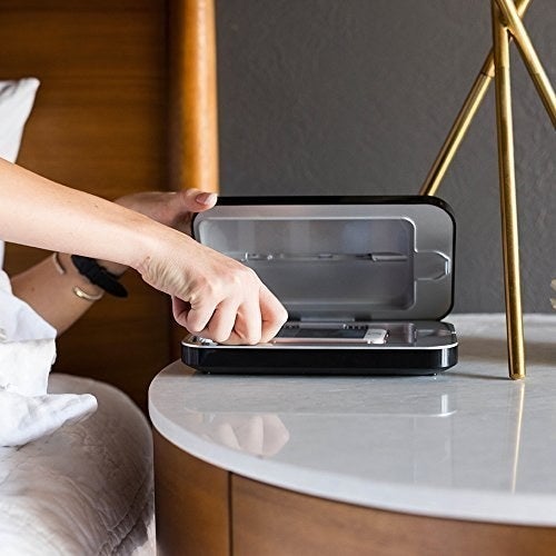 closeup of hand grabbing phone out of case set on side table