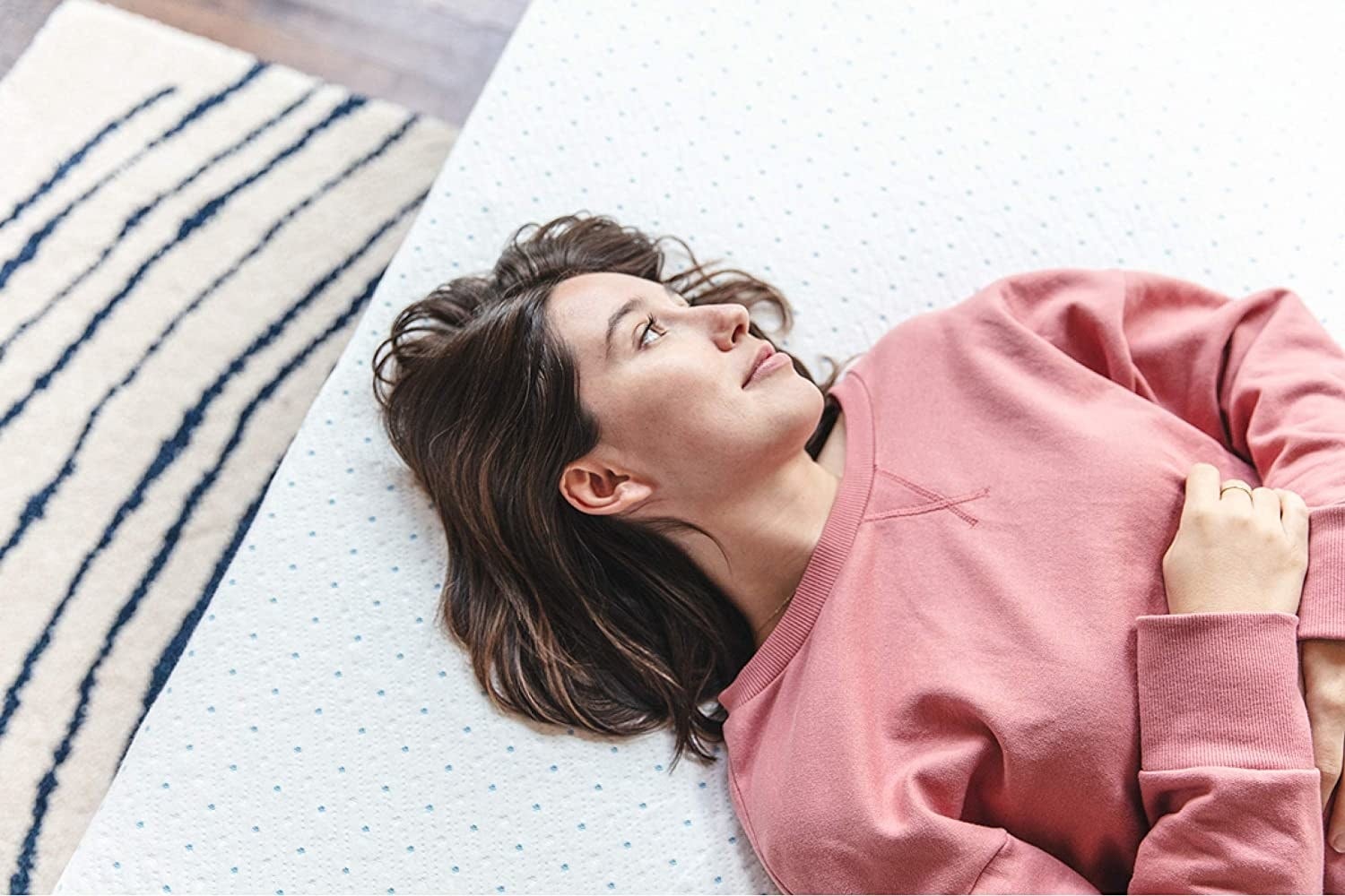 a model lying on top of mattress topper
