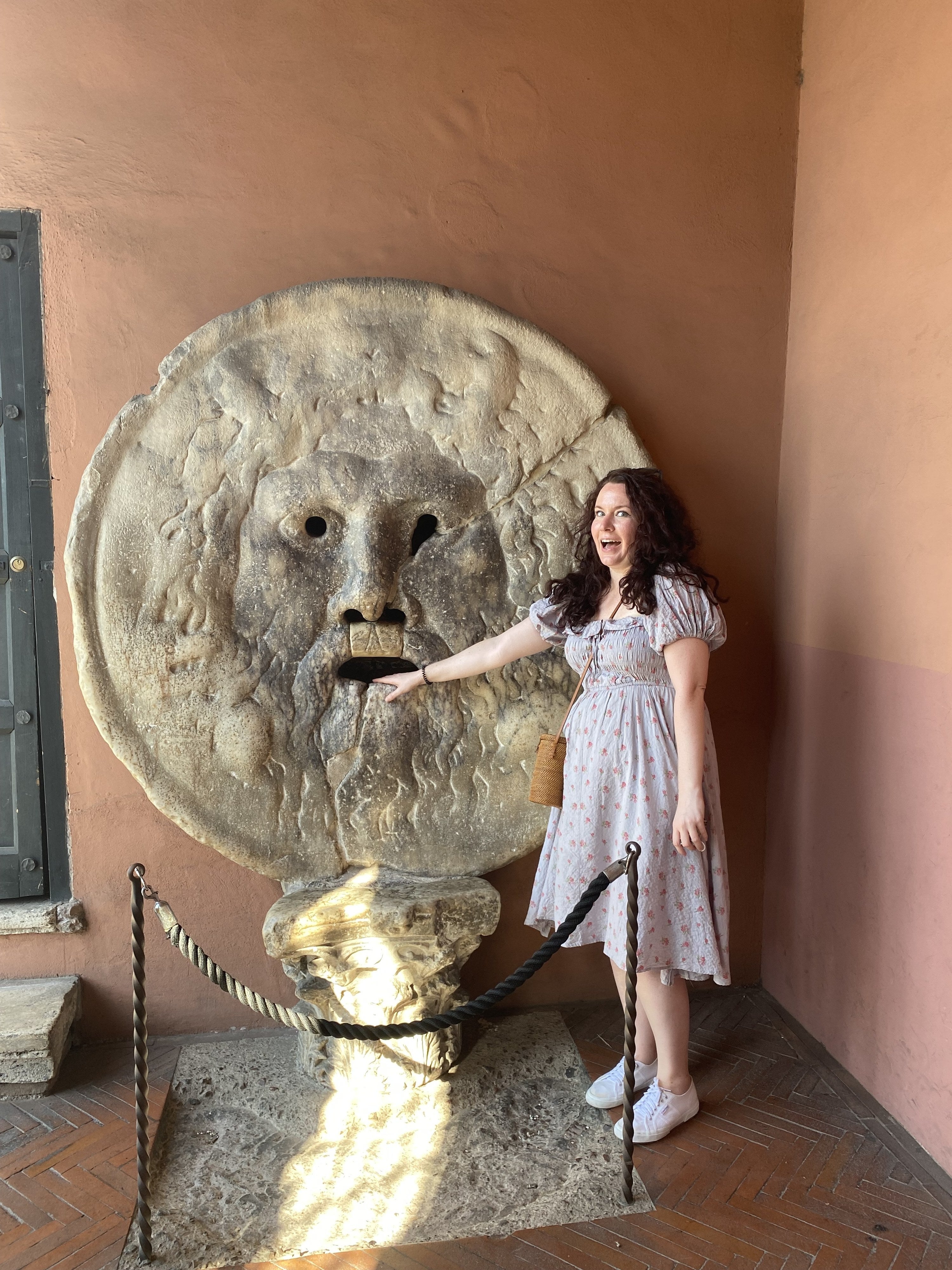 writer wearing the same dress with hand stuck in mouth of a statue