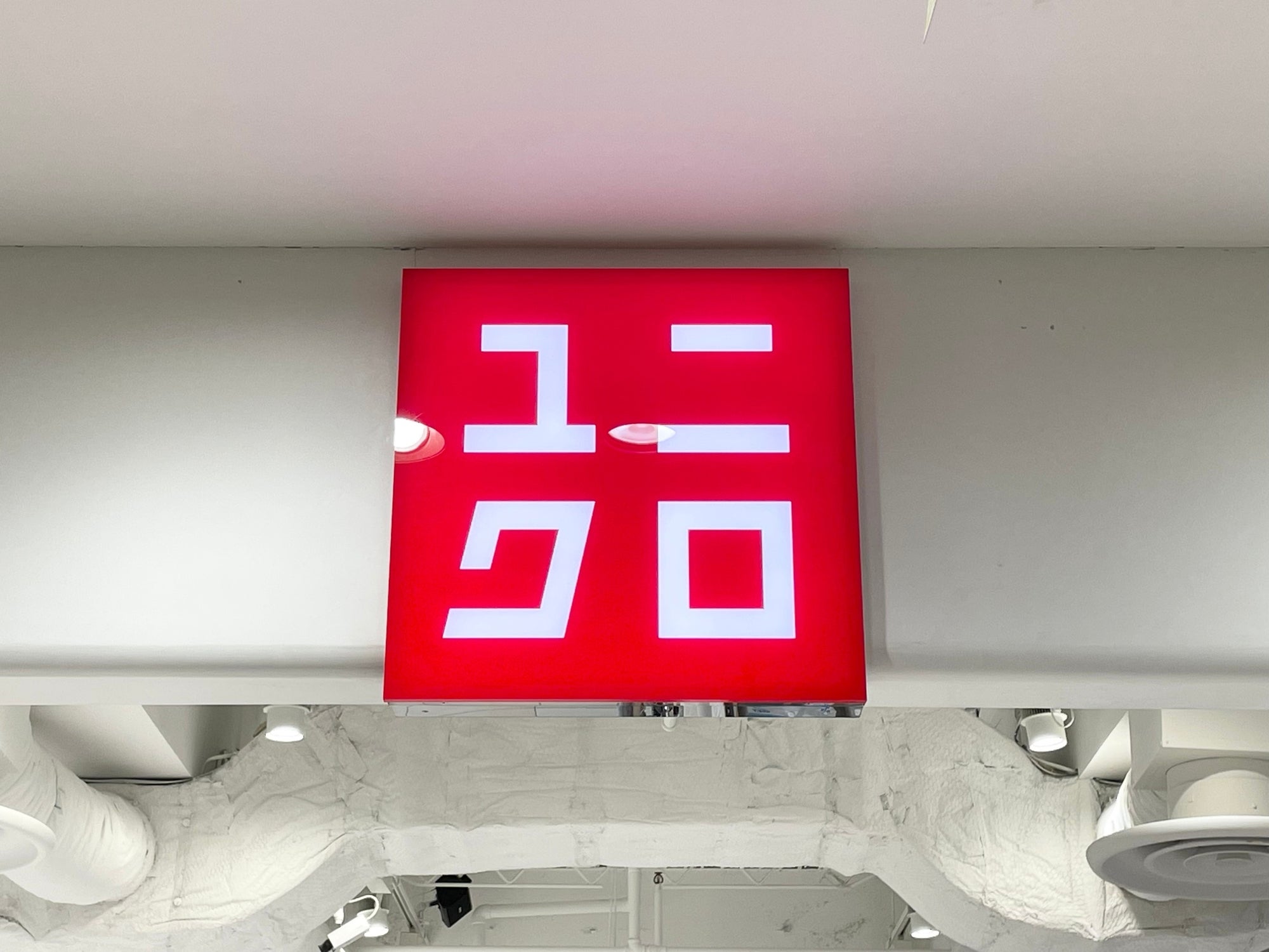 Sign with stylized, blocky, red and white Japanese characters on a storefront, often associated with a popular clothing retailer