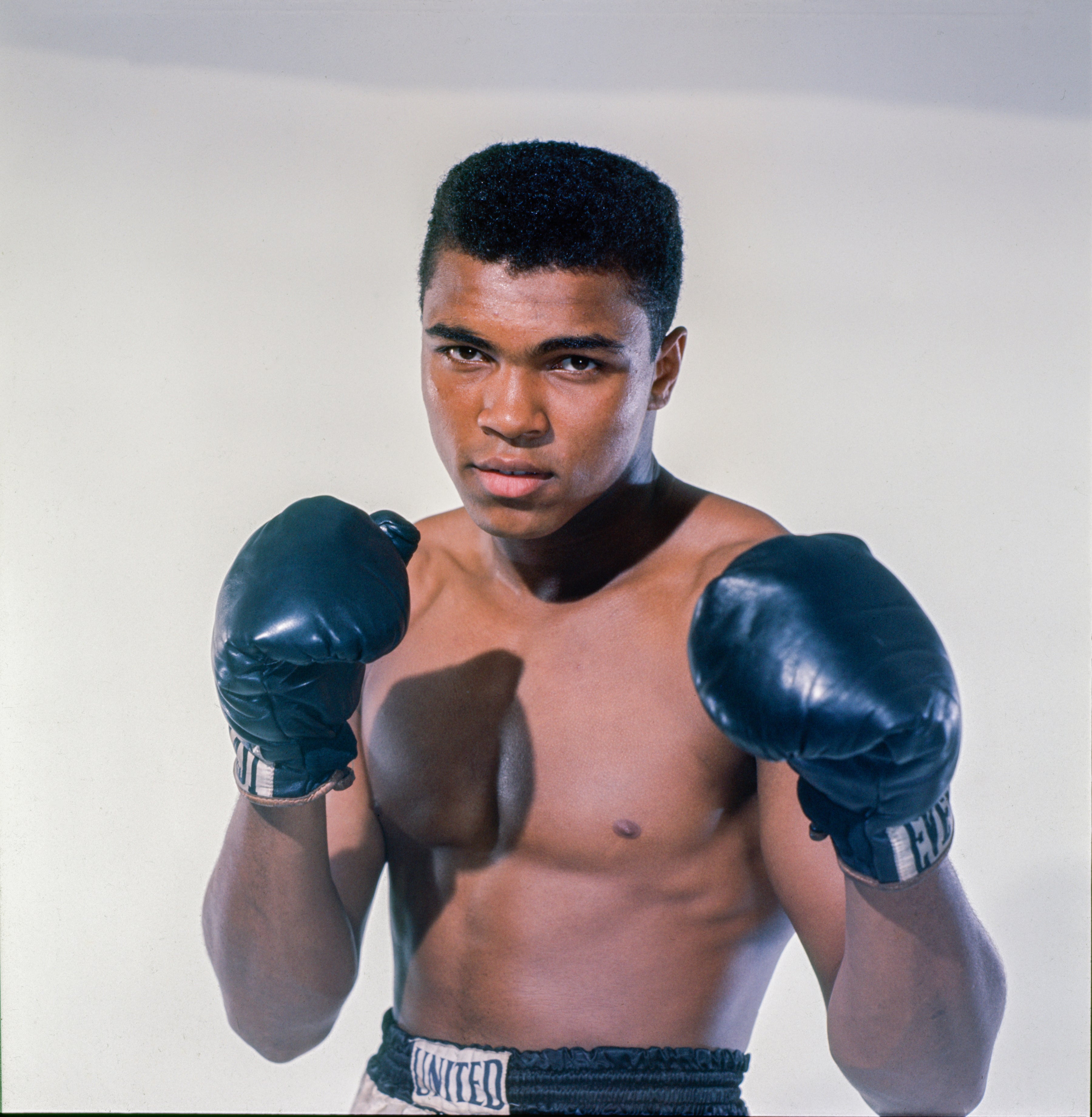 A boxer poses in a classic fighting stance wearing boxing gloves and trunks
