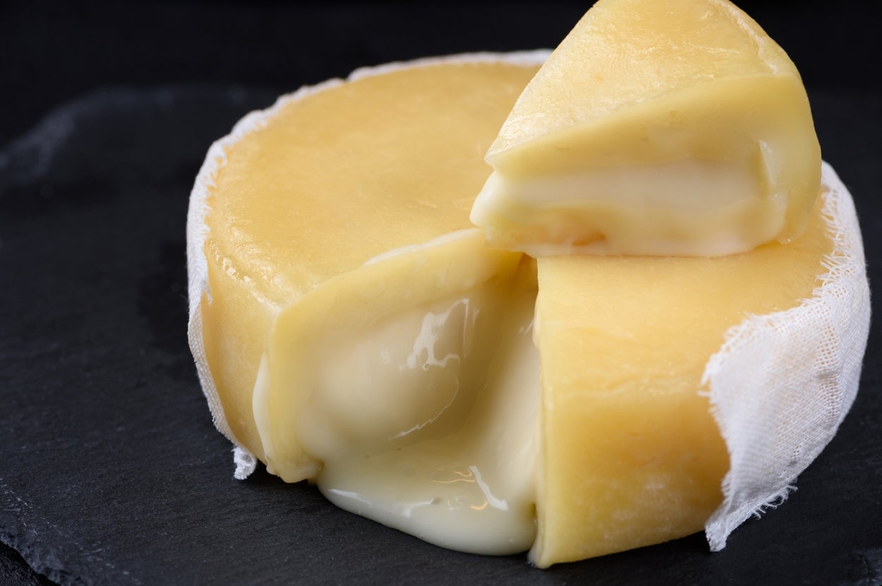 Wheel of soft cheese on a slate board, with a wedge cut out revealing its creamy interior