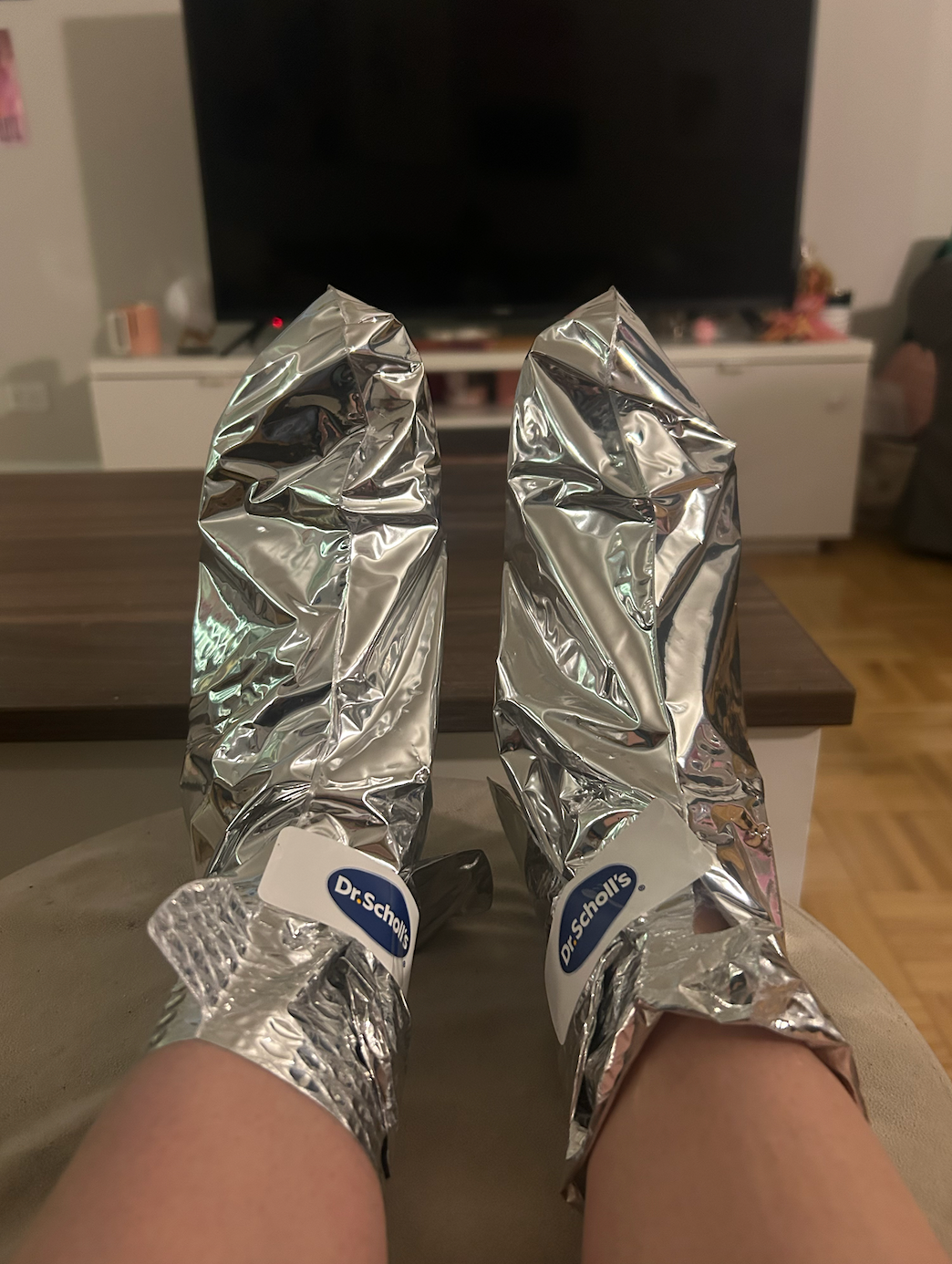Feet propped up with two metallic foot masks on them