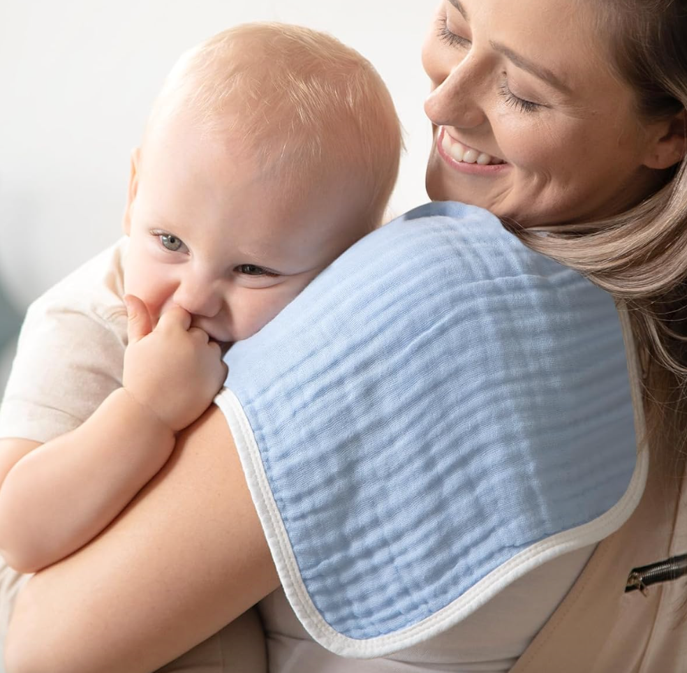 a model holding a baby with a burp cloth over their shoulder
