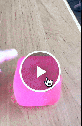 reviewer squishing a pink translucent square shaped stress ball