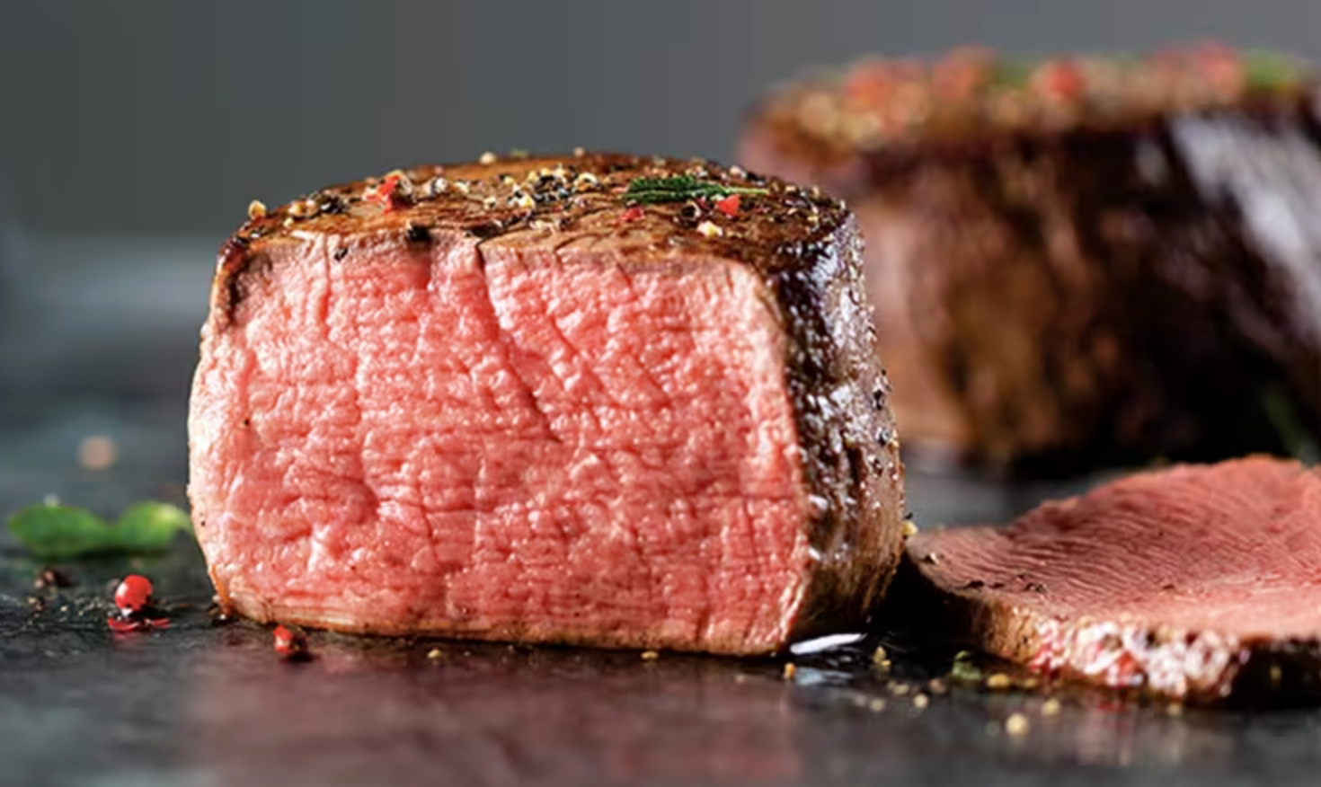 Close-up of a juicy, cooked steak with visible seasoning, showcasing its tender texture
