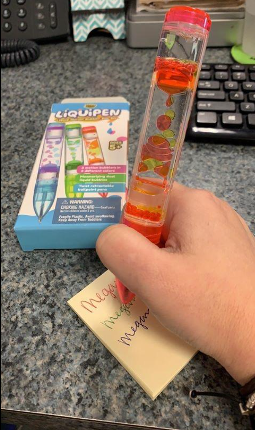 A clear thick pen with orange gel dripping like lava inside of it, writing with orange ink