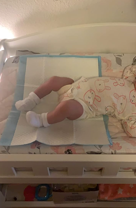 a reviewer's baby on a changing pad with the disposable pad over it