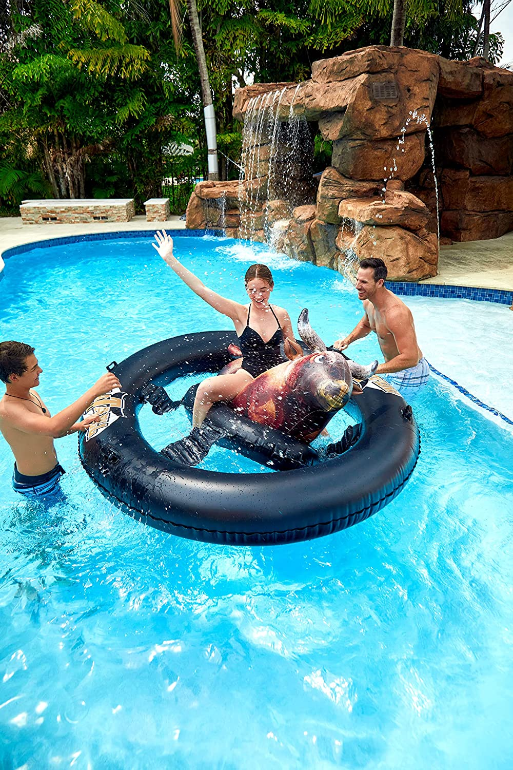 one person on pool float bull while two others push the ring around it