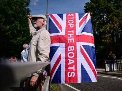 An anti-immigrant protestor holds a Union Flag reading 'Stop The Boats' during a protest o