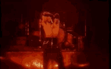 a man is standing in front of a microphone on a stage in a dark room .