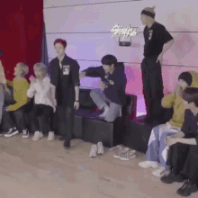 a group of young men are standing and sitting on a stage .