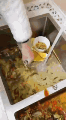 a person is washing dishes in a sink with a spoon .