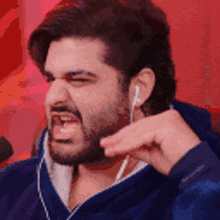 a man with a beard is wearing earphones and making a funny face .