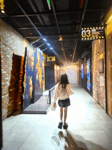 a girl is walking down a hallway with a sign that says 03